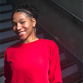 Student Matijanay Tiggle standing in front of stairs in red blouse